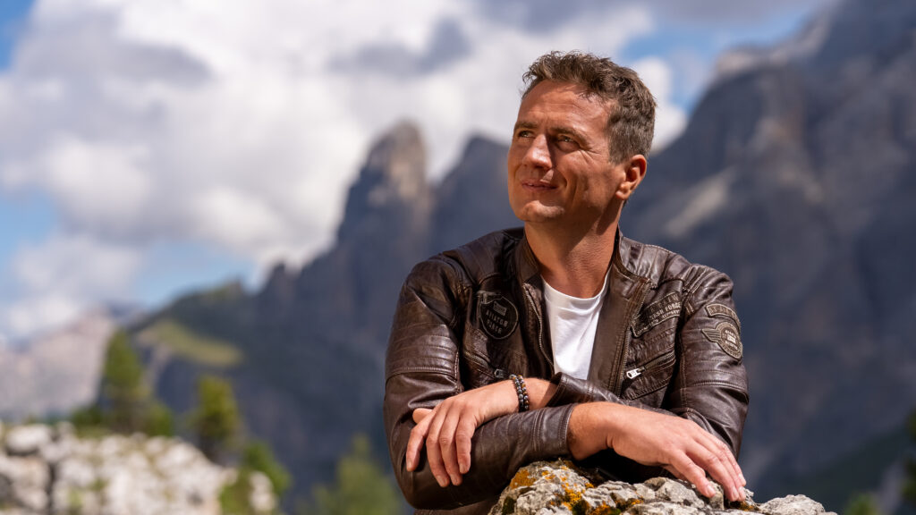Alexander Rier beim Kampagnenshooting in der Steinernen Stadt am Sellajoch, in Lederjacke vor der Bergkulisse